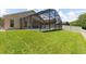 This home features a vast green lawn that leads to a screened-in pool area at 14155 Portrush Dr, Orlando, FL 32828