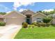 Inviting single-Gathering home with a manicured lawn, beige siding, and an attached two-car garage at 14155 Portrush Dr, Orlando, FL 32828