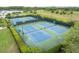 Scenic view of multiple tennis courts surrounded by lush landscaping and a serene lake at 14155 Portrush Dr, Orlando, FL 32828