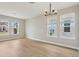 Bright, open living room featuring large windows and a modern chandelier, complemented by wood-look flooring at 16460 Silver Brook Way, Winter Garden, FL 34787
