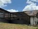 View of the home's screened-in porch and roof with blue tarp on a sunny day at 2120 Lakebreeze Way, Deltona, FL 32738