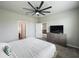 Neutral-toned bedroom featuring a ceiling fan, gray dresser, a television and doorway view to the living area at 2241 Mystic Maze Ln, Minneola, FL 34715