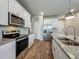 Bright kitchen featuring stainless steel appliances, white cabinets, granite countertops, and hardwood floors at 2241 Mystic Maze Ln, Minneola, FL 34715