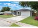 A well-kept lawn leads to a gray home featuring a two-car garage and lush green trees in the background at 2755 Abbey Ave, Orlando, FL 32833