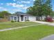 Landscaped front yard with green grass leading to a charming gray single-story home with an attached garage at 2755 Abbey Ave, Orlando, FL 32833