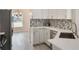 Bright kitchen featuring white cabinets, grey backsplash, stainless steel appliances, and an adjacent dining area at 2755 Abbey Ave, Orlando, FL 32833