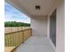 A covered balcony features light colored walls and a wood railing overlooking the lawn at 31836 Sybil Ave, Sorrento, FL 32776