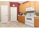 Well-lit kitchen features light wood cabinets, white appliances and tiled floors at 4201 Old Trafford Way, Orlando, FL 32810