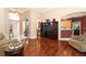 Open-concept living room with hardwood floors, a large TV entertainment center, and a view into the kitchen at 4201 Old Trafford Way, Orlando, FL 32810