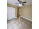 Neutral bedroom with tile flooring, closet, ceiling fan, and adjacent bathroom at 440 Martigues Dr, Kissimmee, FL 34759