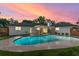 Stunning backyard pool at dusk with covered patio seating, and lush landscaping at 4804 Oakbrooke Pl, Orlando, FL 32812