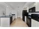 Open-concept kitchen featuring white cabinets, black appliances, and light wood-look flooring at 717 Pine Ter, Altamonte Springs, FL 32714