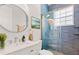 Modern bathroom featuring a glass-enclosed shower with blue tiling, a round mirror, and neutral accents at 7978 Sea Pearl Cir, Kissimmee, FL 34747