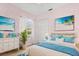 Serene bedroom with beach-themed art, light pink walls, and a soft blue accent blanket at 7978 Sea Pearl Cir, Kissimmee, FL 34747