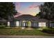 Charming home with arched windows, a landscaped yard, and mature trees at dusk at 7978 Sea Pearl Cir, Kissimmee, FL 34747