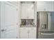 Pristine white kitchen cabinetry and stainless steel refrigerator sit against a gray tiled backsplash and light countertop at 8907 Fallen Oak, Davenport, FL 33897