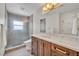 Bathroom featuring wood cabinets, marble countertop, framed mirror and tiled shower with glass doors at 940 Lincoln Cir, Winter Park, FL 32789
