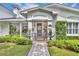 Charming home entrance featuring manicured shrubs, a brick pathway, and covered porch at 940 Lincoln Cir, Winter Park, FL 32789