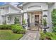 Charming home entrance featuring manicured shrubs, a brick pathway, and covered porch at 940 Lincoln Cir, Winter Park, FL 32789