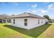 View of the home's back exterior, showcasing windows, patio, and well-maintained lawn at 1119 Union Ave, Mascotte, FL 34753