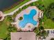 Aerial view of community pool, surrounded by palm trees, green lawns, and a pond at 11918 Nautica Dr, Orlando, FL 32827