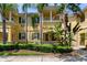 Inviting yellow townhome featuring lush tropical landscaping and a well-manicured lawn at 11918 Nautica Dr, Orlando, FL 32827