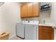 Functional laundry room with washer, dryer, utility sink, cabinet storage, and tile flooring at 11918 Nautica Dr, Orlando, FL 32827