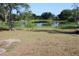 Backyard area with grass and scattered trees, pond and foliage in the background at 1364 Gainesville Dr, Deltona, FL 32725