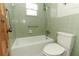 Bathroom featuring a green tiled shower-tub combo, grab bar, and toilet at 1405 Paula Dr, Apopka, FL 32703