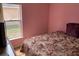 Small bedroom with a floral bedspread, a large window, and pink walls at 1585 Stefan Cole Ln, Apopka, FL 32703