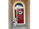 A welcoming red front door adorned with a white flower wreath and 'Welcome' sign, inviting you into this charming home at 1585 Stefan Cole Ln, Apopka, FL 32703
