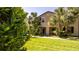 Charming home with lush green lawn and tall palm trees, showcasing the building's architectural details and inviting entrance at 2030 Majorca Dr, Kissimmee, FL 34747