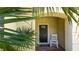 Charming front entrance with a black door, white rocking chair, and tropical landscaping at 2030 Majorca Dr, Kissimmee, FL 34747