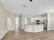 Spacious open-concept living space with hardwood floors, white cabinets, and modern stainless steel appliances at 2468 Cimmaron Ash Way, Apopka, FL 32703