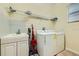 Bright laundry room with washer, dryer, utility sink, white cabinets, and convenient shelving for storage at 2999 Buccaneer Palm Rd, Kissimmee, FL 34747