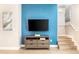 Living room featuring a blue accent wall, TV, and stairs at 3069 White Orchid Rd, Kissimmee, FL 34747