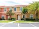 Inviting townhouse exterior featuring a terra cotta roof, well-kept lawn, and vibrant landscaping at 3069 White Orchid Rd, Kissimmee, FL 34747