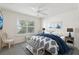 Bright bedroom with a ceiling fan, neutral walls, window with shade, and a bed with a navy and white pattern at 3198 Abana Path, The Villages, FL 32163