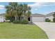 Charming single-story home featuring a two-car garage, well-maintained lawn, and mature palm trees at 3198 Abana Path, The Villages, FL 32163