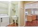 Laundry room and sink next to the kitchen area with wood floors and neutral walls, and white shelves at 3198 Abana Path, The Villages, FL 32163