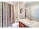 Well-lit bathroom showcasing a shower with patterned curtain and vanity with cabinet at 3380 Pawleys N Loop, St Cloud, FL 34769