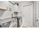 Functional laundry room with modern washer and dryer units, white cabinets, and convenient access door at 3380 Pawleys N Loop, St Cloud, FL 34769