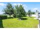 Grassy backyard with mature trees and a partially fenced perimeter under a clear blue sky at 3519 Fernanda Dr, Deltona, FL 32738