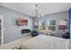 Sunlit bedroom featuring a mounted TV, electric fireplace, chair, and neutral decor at 3519 Fernanda Dr, Deltona, FL 32738