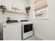 Well-lit laundry area featuring modern appliances and a stylish shelf with decorative items at 3981 Great Smokey Way, Apopka, FL 32712