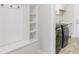Mudroom with built-in shelving, coat hooks, and black front-load washer and dryer at 4119 Sunset Preserve Blvd, Orlando, FL 32820