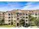 Multi-story condo building with multiple balconies and a well-maintained facade, surrounded by mature trees and landscaping at 5276 Cane Island Loop # 302, Kissimmee, FL 34746