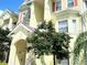 Exterior of a condo building featuring multiple units, balconies, and lush landscaping with mature trees at 5276 Cane Island Loop # 302, Kissimmee, FL 34746