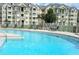 Community pool surrounded by lounge chairs and lush landscaping, perfect for relaxation at 5276 Cane Island Loop # 302, Kissimmee, FL 34746