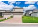 A view of the home's garages, paved driveway, and neatly manicured lawn on a sunny day at 6132 Bimini Twist Loop, Orlando, FL 32819